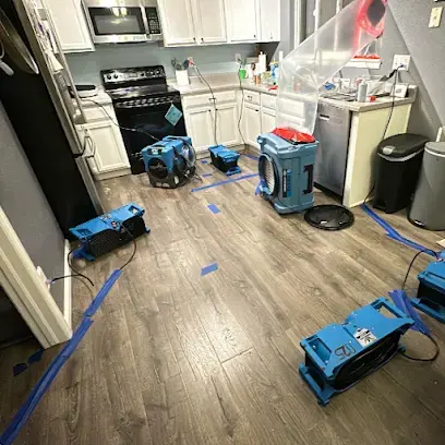 Air movers and dehumidifiers drying a kitchen floor after a leak