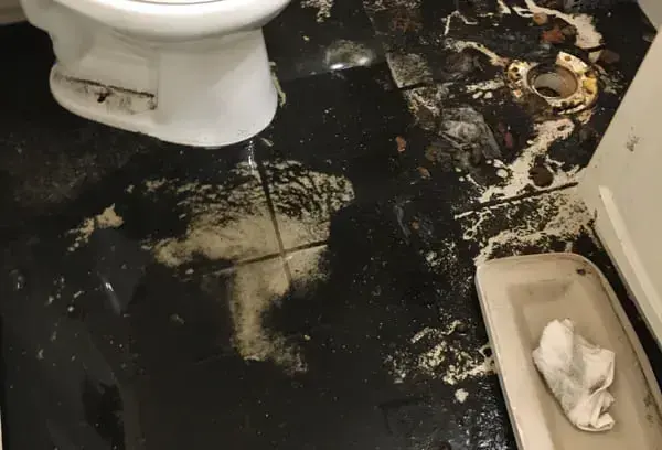 Sewage backup spread across a bathroom floor around a toilet