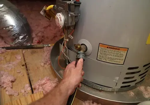 Hand closing the valve on an attic water heater in a North Texas home
